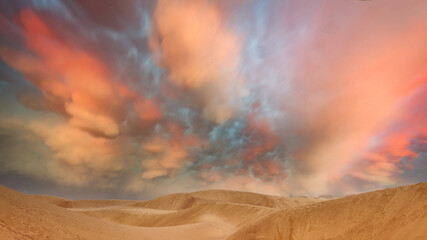 Dunes in the desert with a grand orange sky at sunset