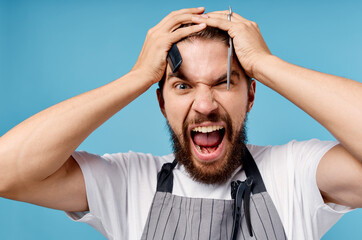 Wall Mural - emotional male hairdresser with scissors and comb model beard gray apron cropped view