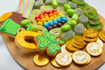 Wooden board with different sweets for St. Patrick's Day celebration on blue background