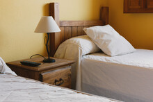 A Room With Two Wooden Beds And A Bedside Table In A Small Spanish Country Hotel.