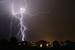 lightning bolts striking near suburban houses at night