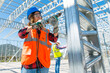 © bulentbaris - The professional young women worker works on installation of a metal frame using drill to screw and young engineer looking at the blueprint