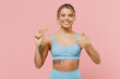 © ViDi Studio - Young strong sporty athletic fitness trainer instructor woman wear blue tracksuit spend time in home gym eat snack show thumb up isolated on pastel plain light pink background. Workout sport concept.
