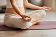 © Seventyfour - Close-up of young pregnant woman sitting on exercise mat and meditating during her training