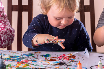 Happy childr girl painting images with fingers. Concept: carefree happy childhood, learning art and creativity. Horizontal image.