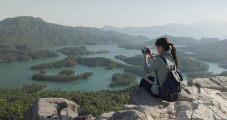 Canvas Print - Woman take photo on camera and sit on the top of mountain