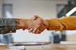 Side view close up of two young men shaking hands at meeting table in office, recruitment and career concept, copy space