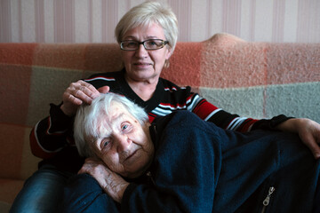 Wall Mural - The old woman laid her head on her adult daughter's lap.