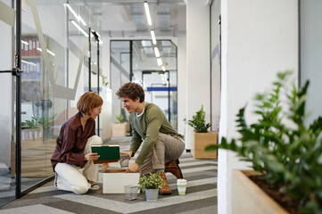 Wall Mural - Full length portrait of friendly colleague helping young employee in office hall, copy space