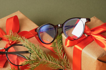 Wall Mural - several fashion eye glasses, fir branch and gift boxes with red ribbon on green background copy space