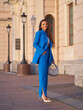 © Dmitry Tsvetkov - Attractive businesswoman wearing stylish blue office pantsuit and high heeled shoes walks with handbag along city historical street at sunset
