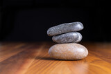 Fototapeta Desenie - Balancing 3 black and beige zen stones on wooden table.