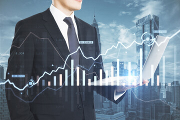 Wall Mural - Close up of businessman hand holding laptop with creative glowing forex chart on blurry city background. Trade, device, financial investment and technology concept. Double exposure.