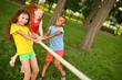 © Evgeniy Kalinovskiy - a group of children compete in a tug of war in the open air against the background of grass and park.