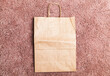 An empty paper bag lays on pink a  carpet