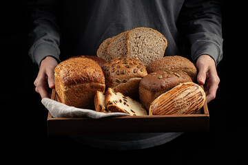 Man holding wooden tray of assorted variety of bread