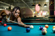 © RomanR - female player playing pool and aiming the billiard ball with cue