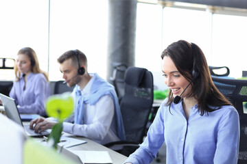 Wall Mural - Portrait of call center worker accompanied by her team. Smiling customer support operator at work.