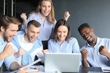 Poster - Happy business people laugh near laptop in the office. Successful team coworkers joke and have fun together at work.