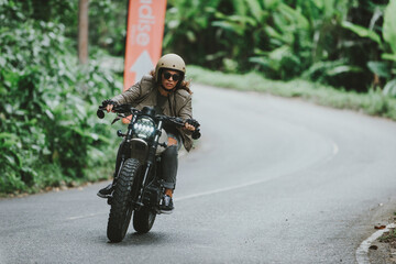 Beautiful girl having fun driving her custom cafe racer motorcycle