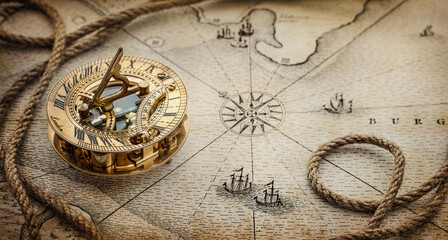 Magnetic old compass  and rope on vintage world map. Travel, geography, navigation, tourism and exploration concept wide background. Macro photo. Very shallow focus.