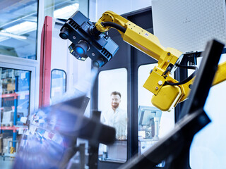 Engineer looking at surveying robot with 3D scan at factory