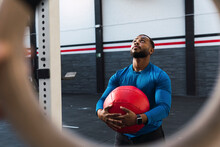 Athlete Looking Up Holding Medicine Ball In Gym