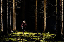 Young Woman Jogging In Forest At Night