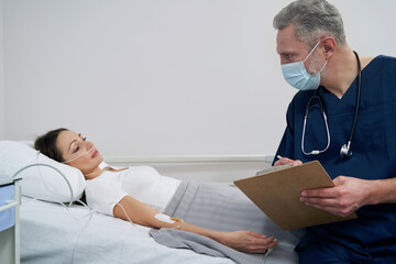 Wall Mural - Doctor assessing young woman health condition during ward round