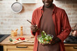 © Seventyfour - Cropped shot of smiling black man mixing salad in glass bowl while enjoying healthy meal in cozy kitchen, copy space