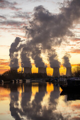 Energy crisis Beautiful dawn sunrise behind coal fired power station with cooling towers smoke plumes into sky. Global warming for electricity generation. Canal boats in cost of living crisis.