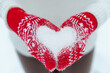 Female hands in knitted mittens with heart of snow in winter day. Love or Valentines day concept