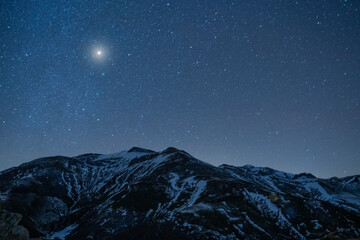 night sky full of stars over snow mountains in winter