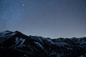 night sky full of stars over snow mountains in winter