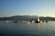 Segelboote liegen im ruhigen Wasser eines Bergsee mit Bergen im Hintergrund und dazu ein harmonisches Abendrot