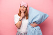 © Asier - Young caucasian woman wearing a pajama holding pillow isolated on pink background looking sideways with doubtful and skeptical expression.