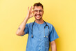 Young nurse caucasian man isolated on yellow background excited keeping ok gesture on eye.