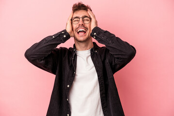 Young caucasian man isolated on pink background laughs joyfully keeping hands on head. Happiness concept.