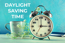 Daylight Saving Time Concept, Spring Forward. A Retro Alarm Clock With A Coffee Cup And Fresh Flowers On A Blue Background