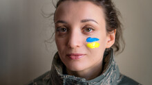 Indoor Portrait Of Young Girl With Blue And Yellow Ukrainian Flag On Her Cheek Wearing Military Uniform, Mandatory Conscription In Ukraine, Equality Concepts