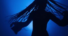 Silhouette Of Young Woman Dancing In Blue Light And Smoke