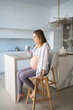 © Татьяна Кочкина - Happy pregnant woman pours into a cup in her kitchen. The concept of motherhood.