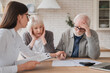 © InsideCreativeHouse - Emotional mental support. Financial adviser consulting senior elderly grandparents couple showing debts, bunkruptcy, negative test results, mortgage, divorce certificate contract pension at home