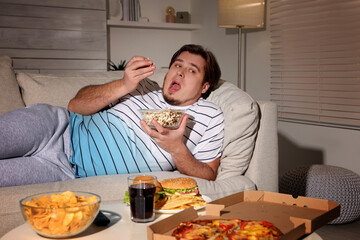 Sticker - Overweight man with bowl of popcorn on sofa at home