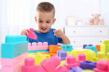 Sticker - Cute little boy playing with colorful building blocks at table in room