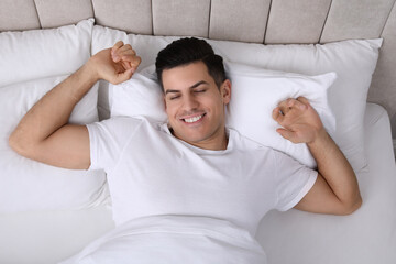 Canvas Print - Happy man awakening in bed at home, top view