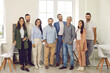 © Studio Romantic - Group portrait of happy confident business professionals and teammates at work. Team of young and mature people in smart casual clothes all together standing in office, looking at camera and smiling
