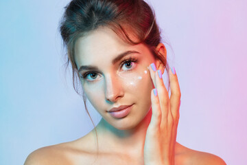 Wall Mural - Beautiful girl with moisturizing cream in  neon light. Beauty and skincare concept.