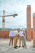 © zinkevych - Concentrated young construction engineer surrounded by his colleagues outdoors