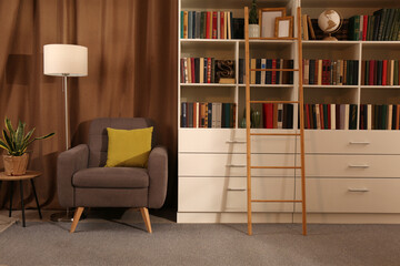 Cozy home library interior with collection of different books on shelves and comfortable place for reading